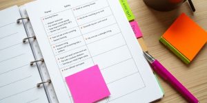 Workspace with planner, sticky notes, and pen for planning.