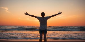 Person embracing themselves on a beach at sunset.