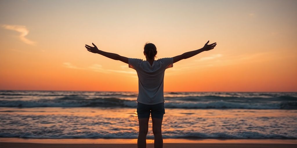 Person embracing themselves on a beach at sunset.