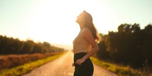 Woman smiling, walking towards bright horizon