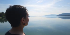 Woman looking at her reflection in a calm lake.